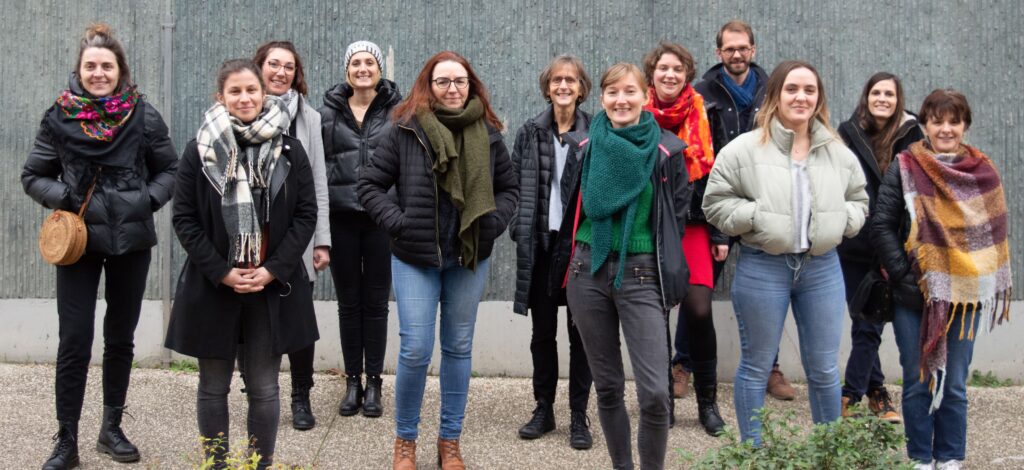 Groupe de personnes face caméra devant un mur, les mains dans les poches